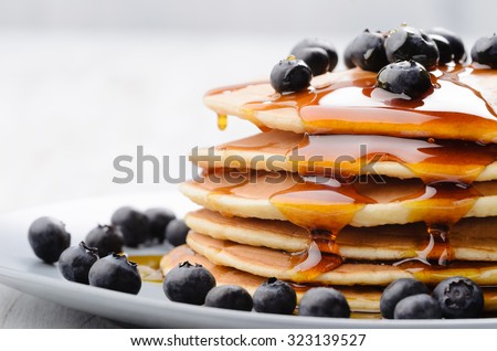 Delicious pancakes close up, with fresh blueberries and maple syrup