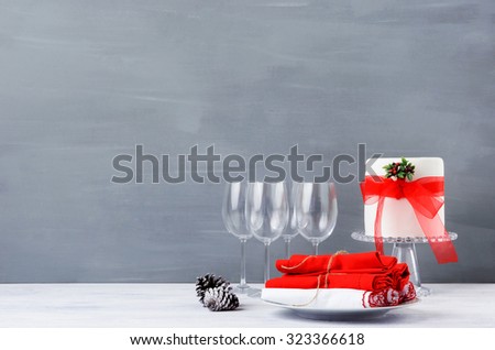 Modern minimalist christmas decoration with crockery, wine glasses and beautifully decorated cake on dark grey background