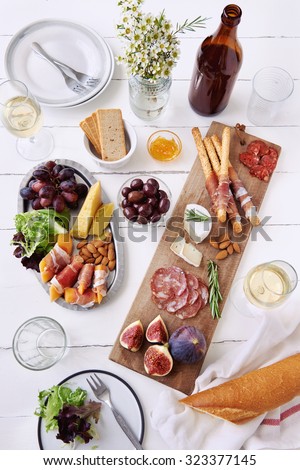 Cheese and cured meat charcuterie selection salami, chorizo, prosciutto wrapped bread sticks with fresh fig, rockmelon, almonds and white wine
