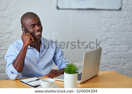 professional african black man talking on mobile cell phone to clients in office with laptop computer