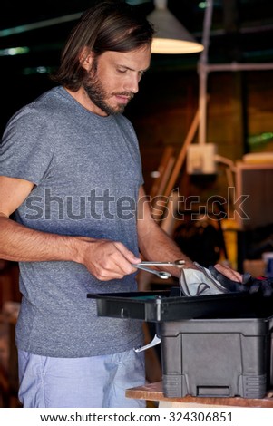 young caucasian arranging his tools in the tool shed garage workshop