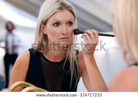 young professional businesswoman applying makeup cosmetics early morning at home bathroom