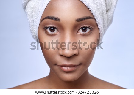 Close up portrait of young beautiful black african woman with towel wrapped around her hair, beauty skincare cosmetics concept
