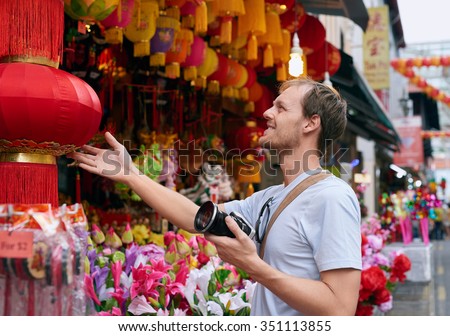 Tourist traveler with camera in modern asian city chinatown shopping looking at a red lantern for souvenir trinkets