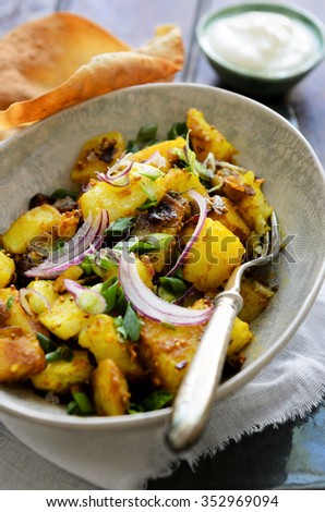 Curry potatoes cooked in asian south indian spices like turmeric and mustard seeds, an elegant ethnic dish served with poppadoms and yoghurt