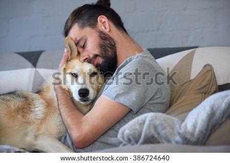hipster man snuggling and hugging his dog, close friendship loving bond between owner and pet husky