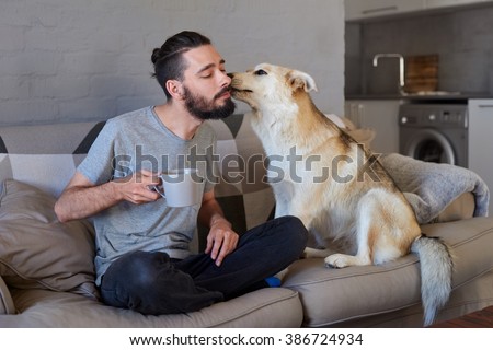 Pet owner receiving a kiss lick from his pet dog on the couch sofa, loving affectionate bond