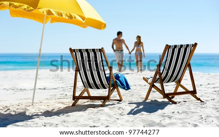 Tropical summer beach holiday couple walk towards the ocean holding hands while on honeymoon vacation