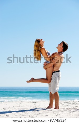 embracing summer beach couple hugging and laughing together on a tropical island