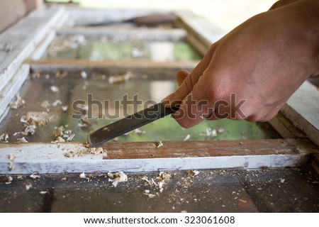 Home Renovation, woman\'s hand removing a white paint from a wooden Window with a Scraper