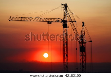 Hoisting cranes and construction site on sunset.