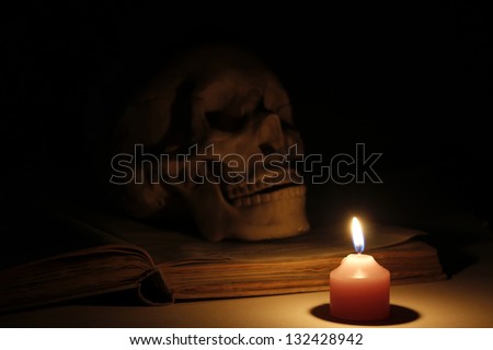 Halloween images, burning candles in a skull and book.