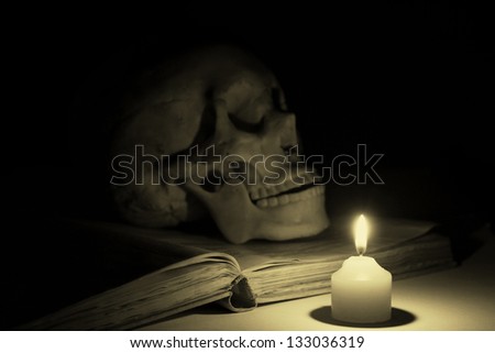 Burning the candle lit the skull and books.