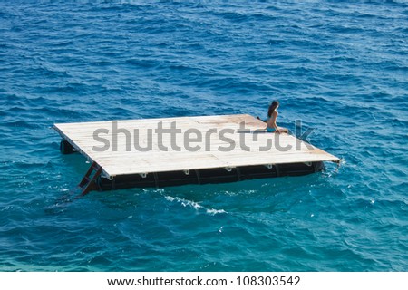 young woman relaxing  on a wooden raft in the sea