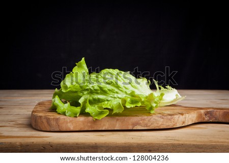 lettuce leaf on cutting board on black background