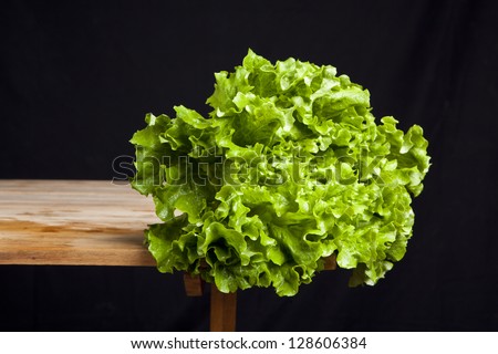 fresh green lettuce on wooden table on black background