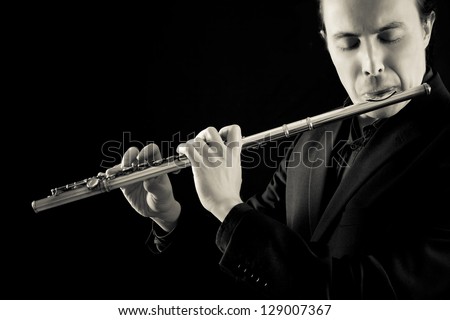 professional flutist musician playing flute on black background