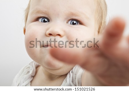 bright closeup portrait of adorable baby trying to reach the camera