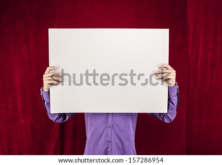 man holding white blank poster on a red velvet background