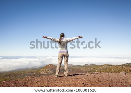 young woman on top of the moutain with the arms raised enjoying freedom  above the clouds, Winner / Success concept.