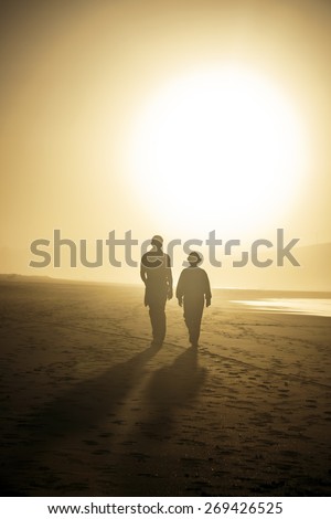 TWO PERSONS WALKING TOWARDS THE SUN