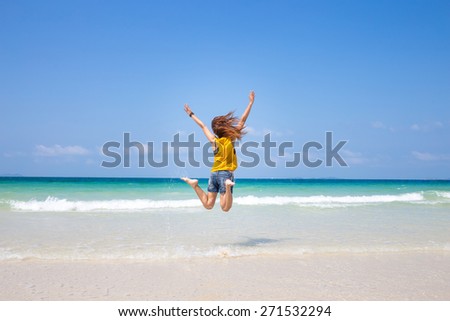 Jumping happy girl on the beach,  woman enjoys wind, freedom, vacation, holiday, summertime fun concept