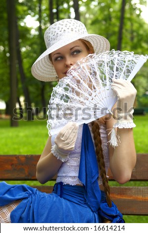 Beautiful young girl with long red hair, white hut and fan in the Summer Garden (Saint Petersburg)