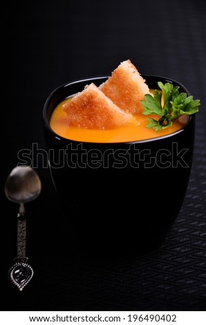 Orange soup in a black cup