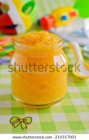 Baby food orange color, resting on a background of children`s toys