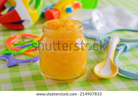 Baby food orange color, resting on a background of children`s toys