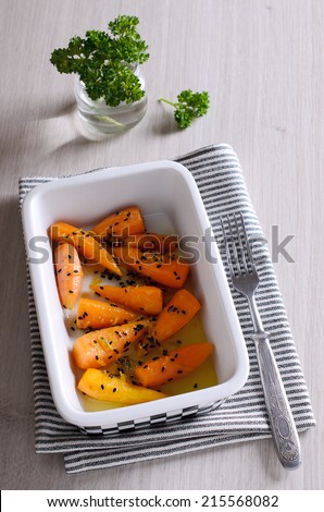 A side dish of baby carrots with black sesame seeds