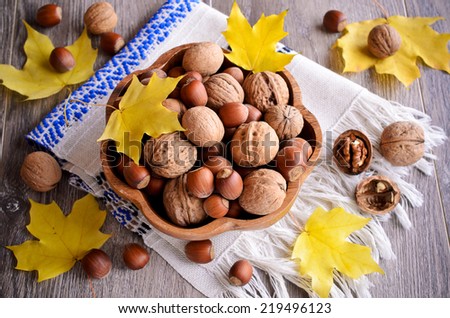 Taken together, walnuts and hazelnuts are in the basket on the maple leaves background