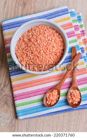Small red lentils is in a blue ceramic bowl on bright striped napkin