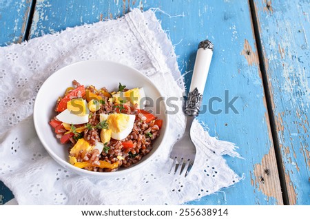 Salad of red rice, paprika and eggs with thyme leaves