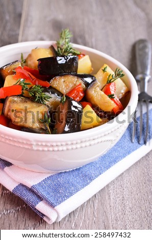Stew slices of eggplant, peppers and potatoes with branches of thyme on the ceramic plate