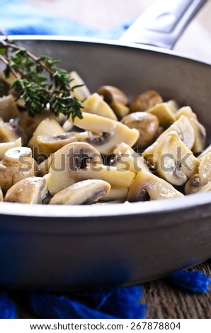 Cooked mushrooms with a branch of thyme in the pan