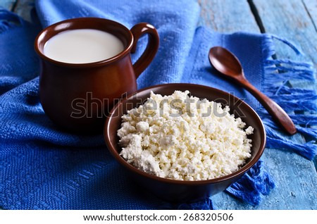 White cheese in ceramic container in the background of milk and yogurt