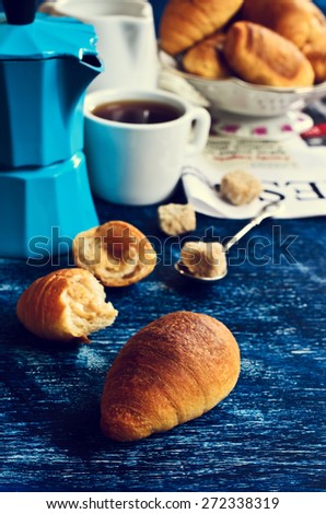 The croissant is on the table amid coffee accessories