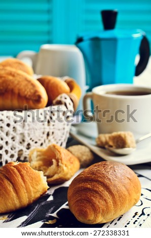 The croissant is on the table amid coffee accessories