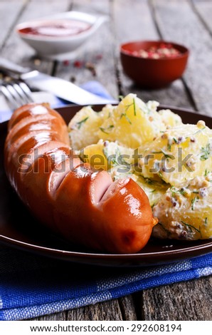 Grilled sausage with incisions with a potato side dish in a ceramic plate