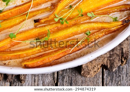 Baked carrots in a baking dish with vegetable oil on a wooden surface