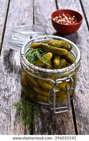 Pickles is a very small amount in a glass jar on a wooden surface