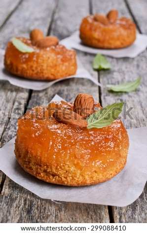 Cake with jam, decorated with almonds and mint, on a wooden surface