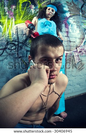 Beautiful girl and attractive boy  working at a graffiti wall. Girl using a drill press, boy using a phone