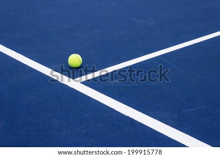 Tennis ball on tennis court. Blue hard surface. Corner of service field. Copy space available.