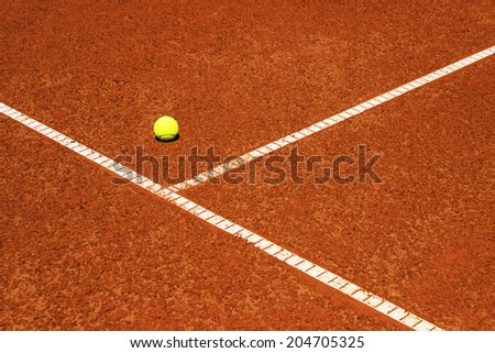 Tennis ball on tennis court. Clay surface. Corner of service field. Copy space available.