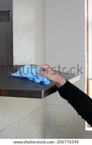 Cleaning the range hood in the kitchen.
