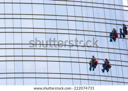 washers clean the facade of the skyscraper window clinging to the ropes