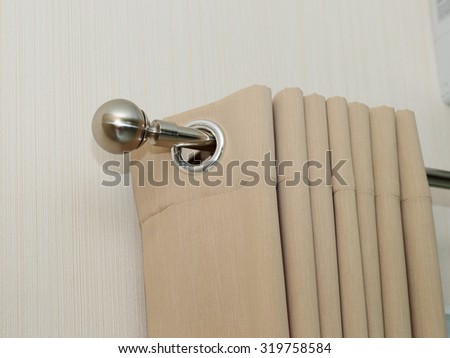 Cream colored curtains In steel rail close up view
