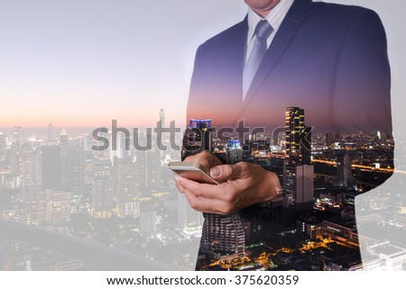 Double exposure of business man hand hold and touch screen smart phone, mobile, street and night city as communication concept.